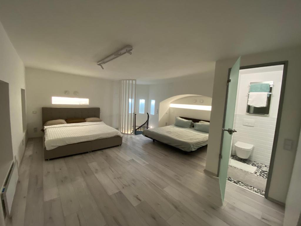 Habitación blanca con 2 camas y suelo de madera. en Brand New Luxury Apartment in Absolute Downtown en Budapest