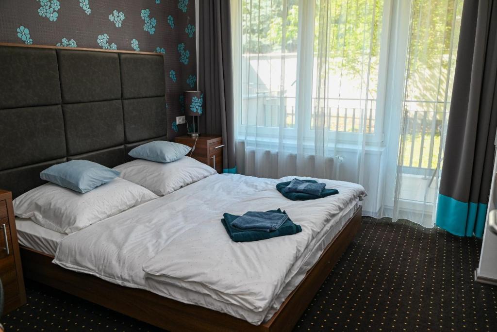 a bedroom with a bed with two blue towels on it at Lara Five in Hajdúszoboszló