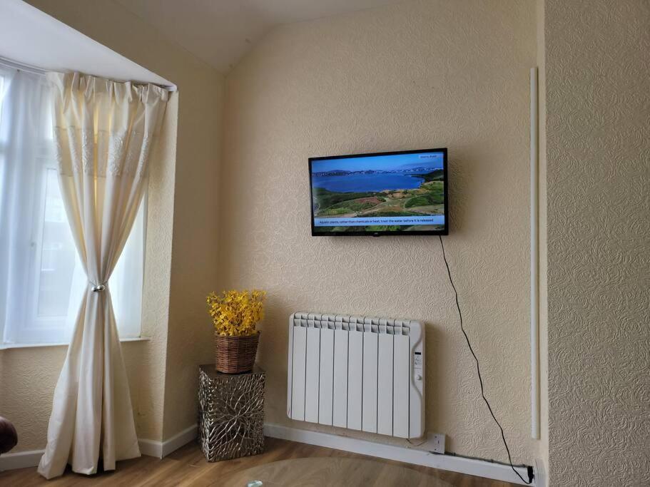 a living room with a television on the wall at Rest & Relax Apartment in Tilehurst