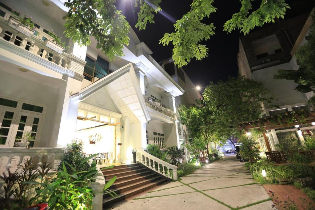 ハイフォンにあるトゥン ヴィ ホテルの夜間の階段と木々が並ぶ大きな白い建物