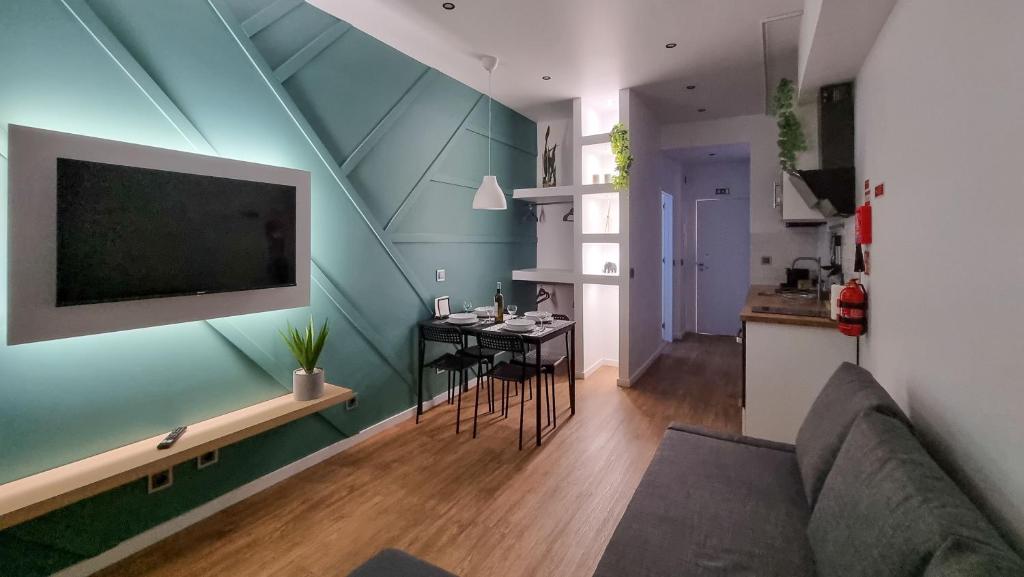 ein Wohnzimmer mit einem Sofa, einem Tisch und einem TV in der Unterkunft The Jolie Apartments - by the Ocean in Porto Moniz