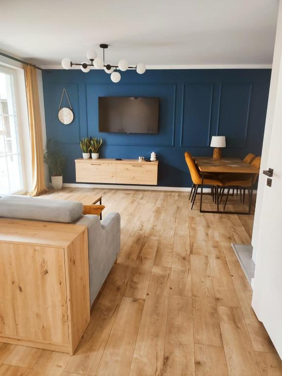 a living room with blue walls and a bed and a table at Miodowy Apartament in Złotów