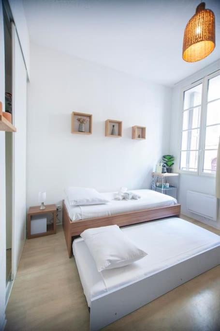two beds in a white room with a lamp at SENAC - Havre citadin, La Canebière in Marseille