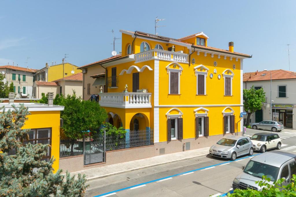 un edificio amarillo con coches estacionados frente a él en La Casa di Bianca, en Follonica