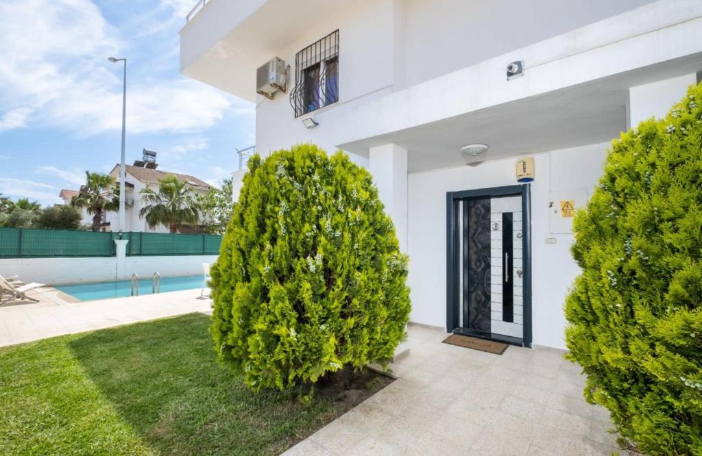 een wit huis met bomen voor een zwembad bij Dazzling Villa with Private Pool in Antalya in Belek