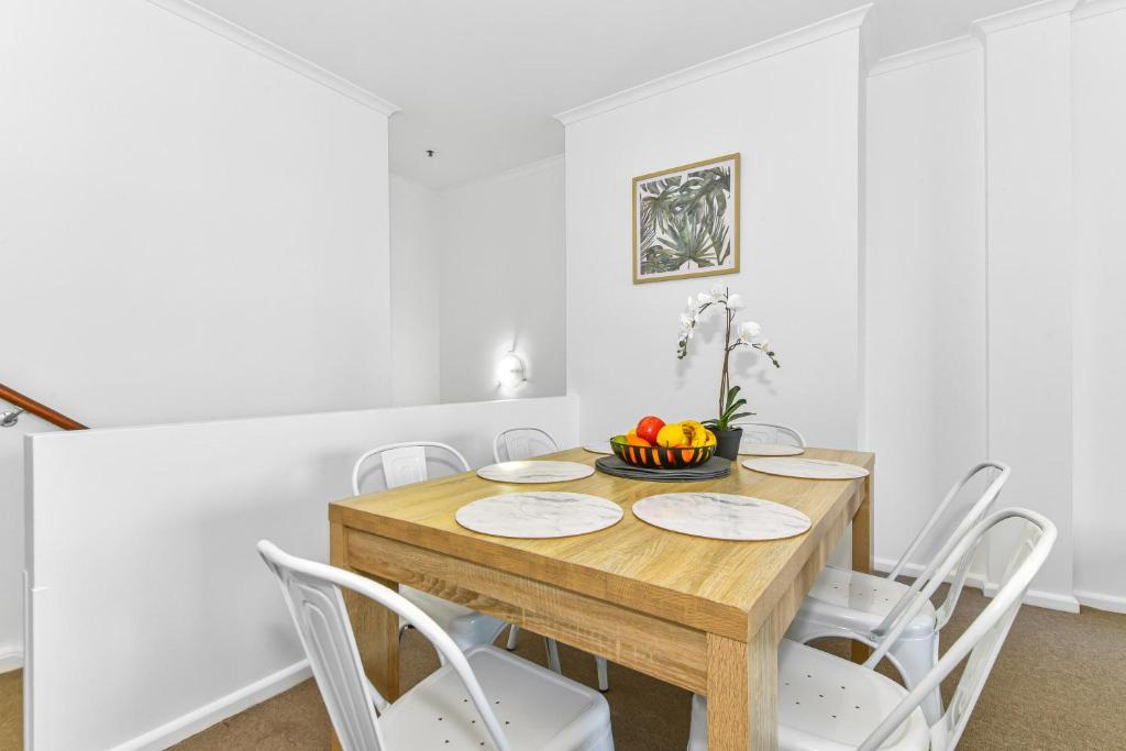 a dining room with a wooden table and white chairs at Goldsbrough 2 bedrooms split apartment in Sydney