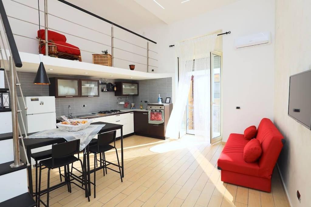 a living room with a red couch and a kitchen at Suite in città in Naples