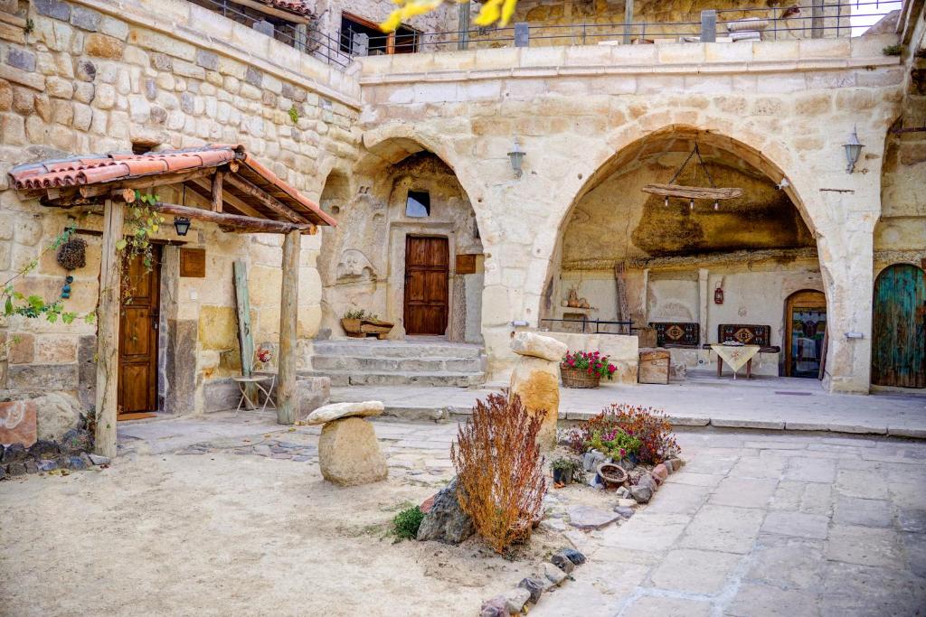 an old stone building with a courtyard with a building with doors at Gibos Cave Hotel in Urgup