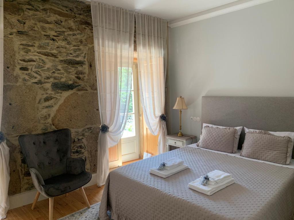 a bedroom with a bed and a chair and a window at Quintal do Grémio in Torre de Moncorvo