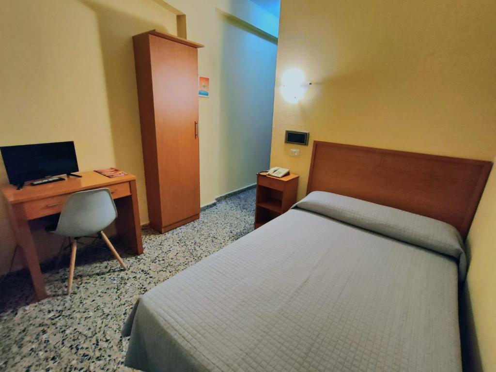 a bedroom with a bed and a desk with a computer at Hotel Cogullada in Zaragoza