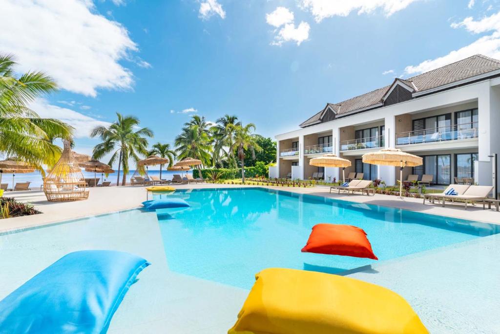 uma piscina num resort com cadeiras e guarda-sóis em Cook's Bay Hotel & Suites em Paopao