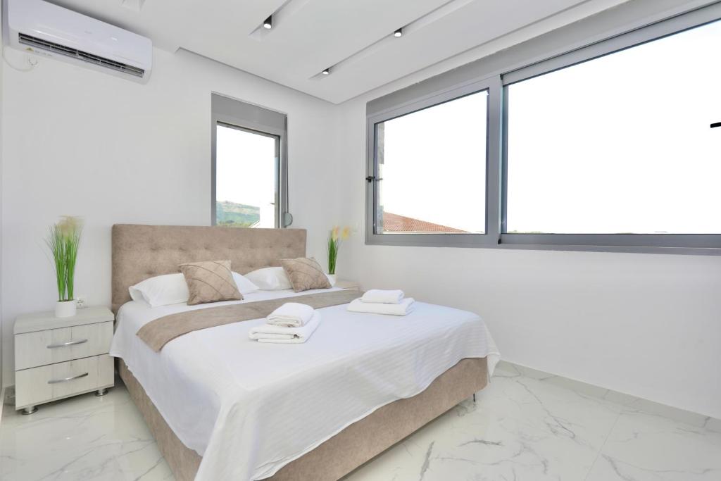 een witte slaapkamer met een groot bed en ramen bij NESI Apartments in Ulcinj