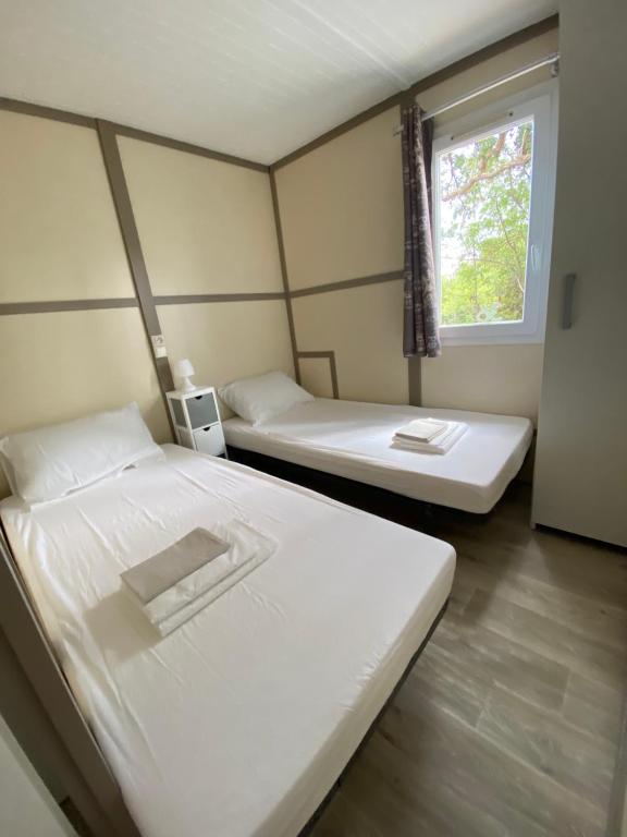 2 camas en una habitación con ventana en Les chalets des Îles, en Borgo