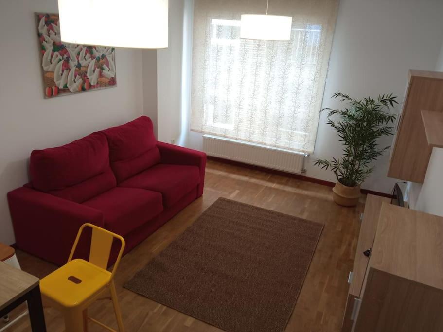 a living room with a red couch and a table at Bonito Apartamento en Aviles in Avilés