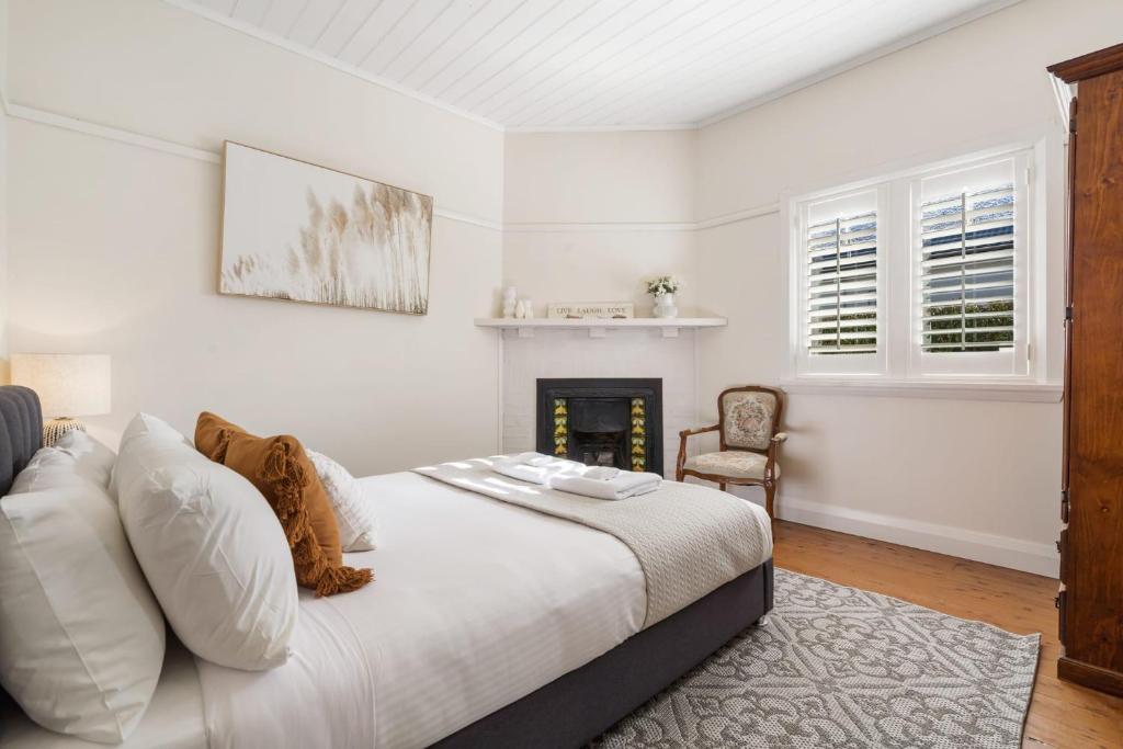 biała sypialnia z łóżkiem i kominkiem w obiekcie Sampson Cottage - Historic Charm w mieście Orange