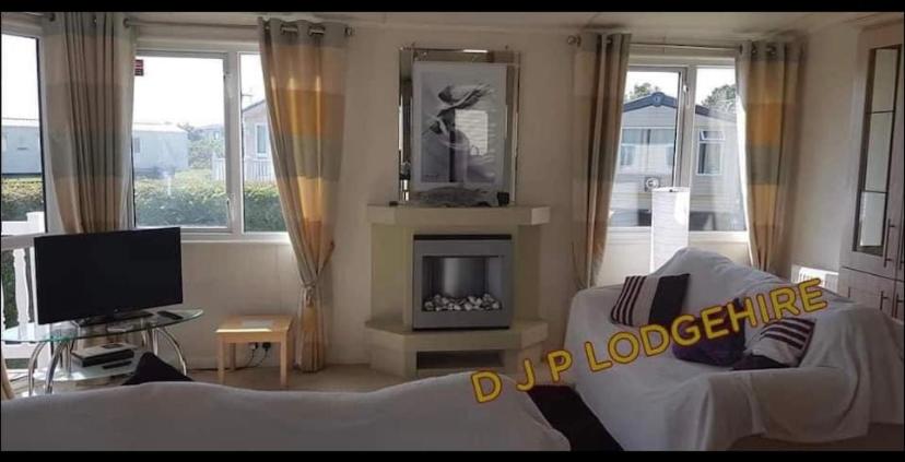 a living room with a white couch and a fireplace at Lodge for Hire in Pagham