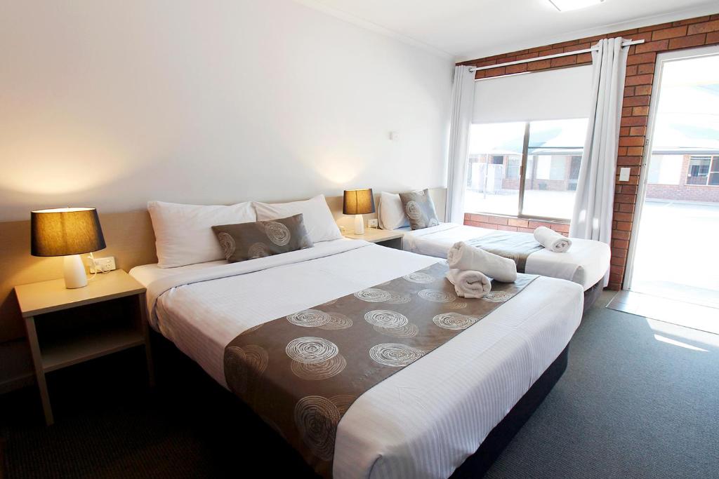 ein Hotelzimmer mit 2 Betten und einem Fenster in der Unterkunft Blue Shades Motel in Maryborough