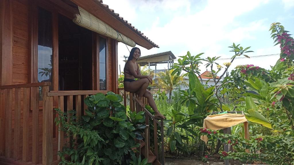 a woman sitting on the railing of a house at Ayolah surf House and Surfcamp in Jembrana
