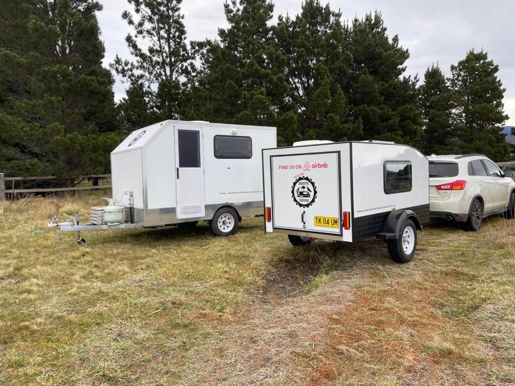 金逹拜恩的住宿－Jindabyne caravan hire，停在田野里的拖车和野营车