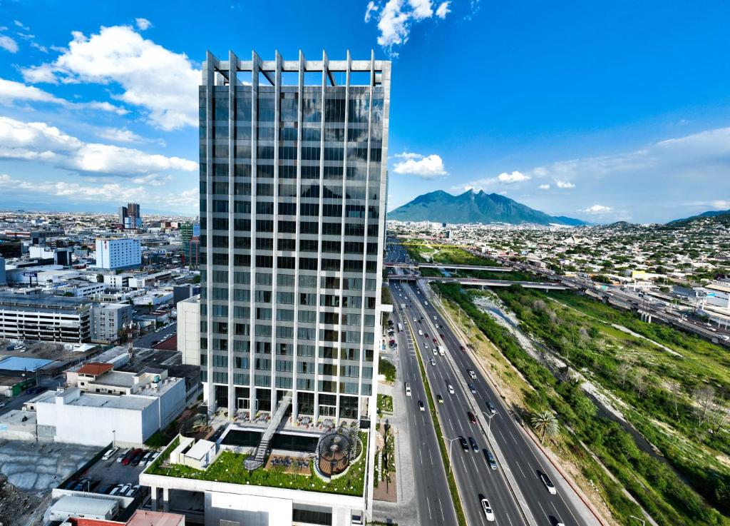 a tall building with a highway in front of a city at Galeria Plaza Monterrey in Monterrey