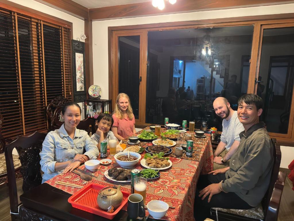 吉婆島的住宿－An Homestay-Stay with local family-Vietnam traditional design room，一群坐在桌子旁吃食物的人