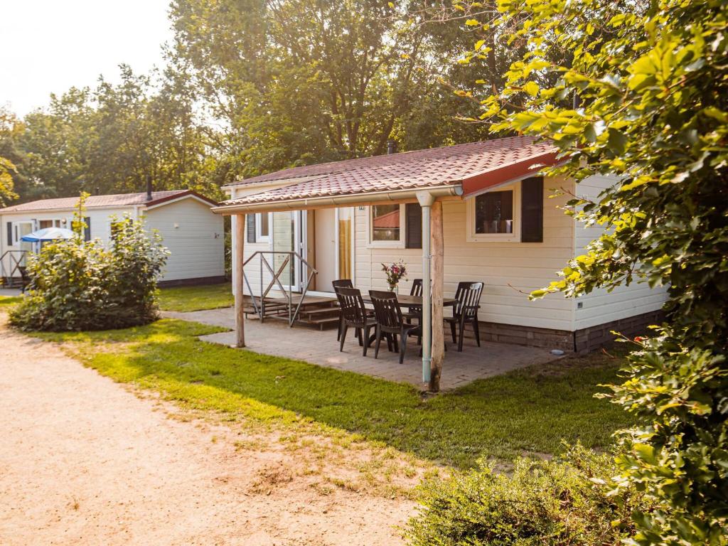 a white house with a table and chairs in the yard at Detached chalet in holiday park swimming pool and on the Leukermeer in Well