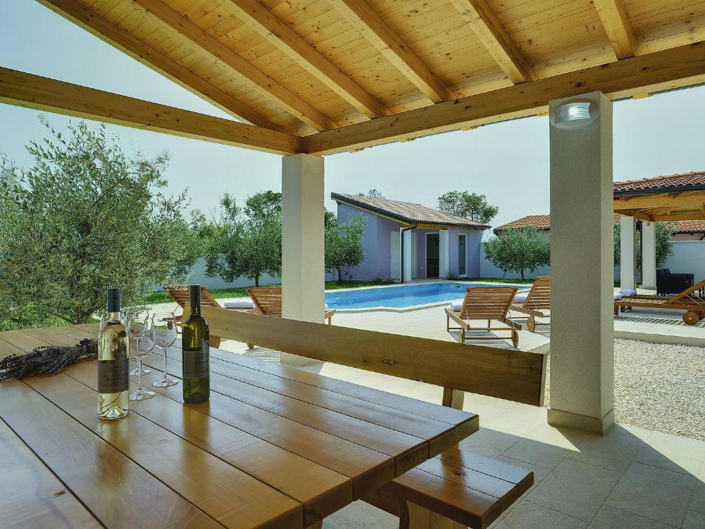 una mesa de madera con 2 botellas de vino en el patio en A wonderful family villa with swimming pool and covered terrace, en Pula