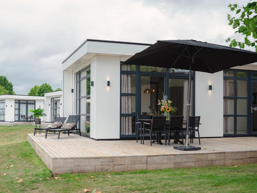 a house with a patio with an umbrella at Luxury holiday home on the water, located in a holiday park in the Betuwe in Maurik