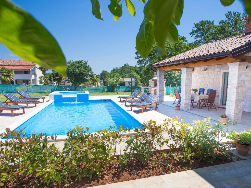 einen Pool mit Stühlen und ein Haus in der Unterkunft Roofed Villa in Istria with Private Pool and Garden in Rajki