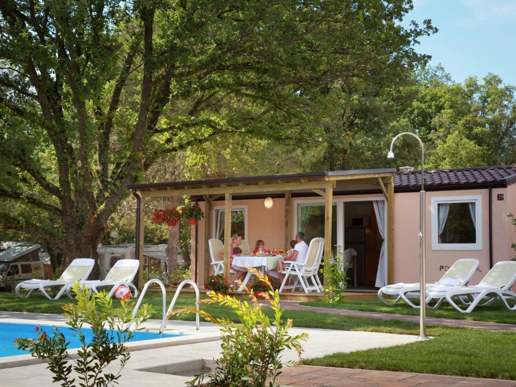 弗爾薩爾的住宿－Modern chalet with 2 bathrooms，坐在泳池旁凉亭桌子旁的家庭