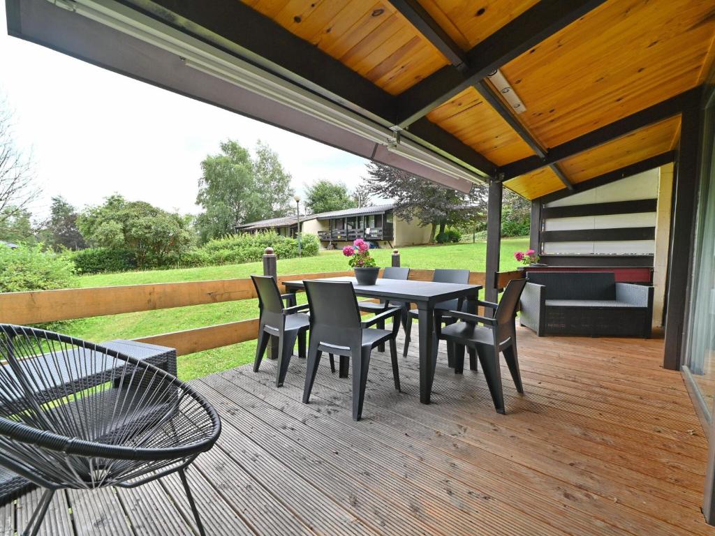 a patio with a table and chairs on a deck at Semi-detached bungalow for 6 people next to the Lac de Vallée de Rabais in Virton