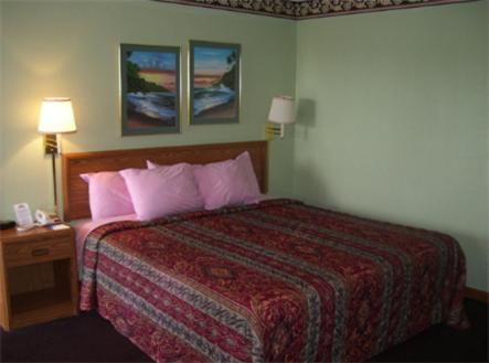 a hotel room with a bed with pink pillows at Regency Inn in Fayetteville