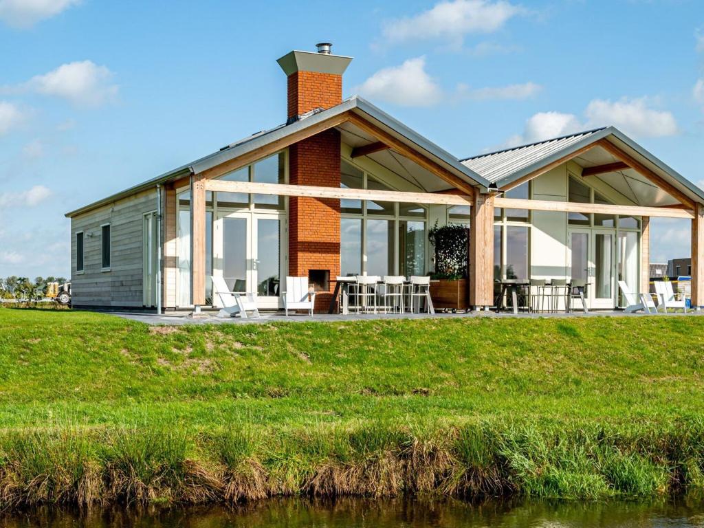 een huis op een heuvel naast een rivier bij Beautiful bungalow with an unobstructed view, on a holiday park in Friesland in Akkrum