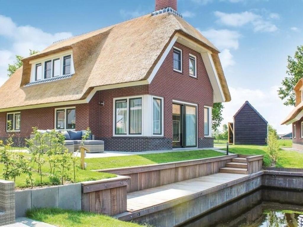 een rood bakstenen huis met een houten loopbrug bij Atmospheric villa on the water, at a holiday park in Friesland in Idskenhuizen