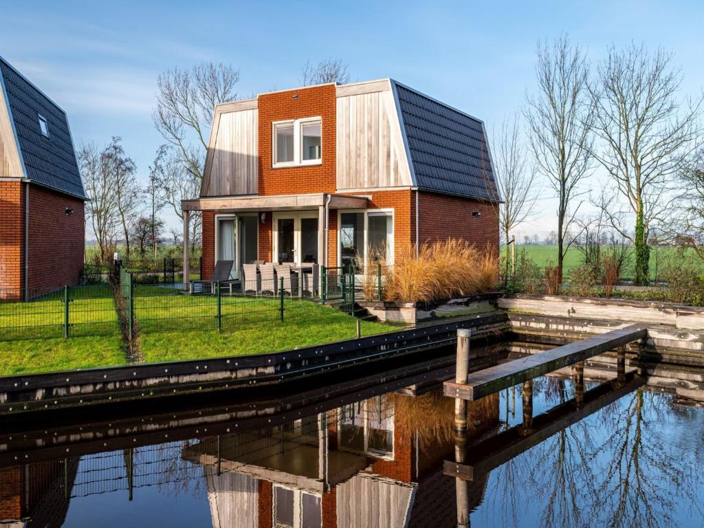 een huis met een reflectie in het water bij Spacious holiday home with outdoor spa, on a holiday park in Friesland in Akkrum