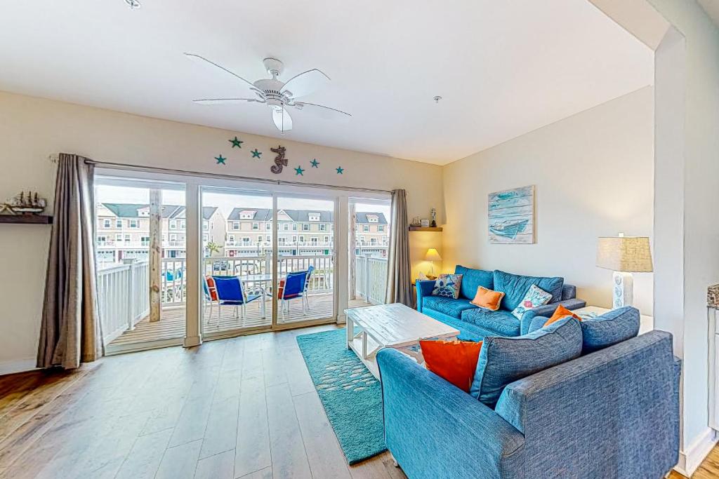 a living room with a blue couch and a balcony at Seaside Village - SunnyG in Ocean City