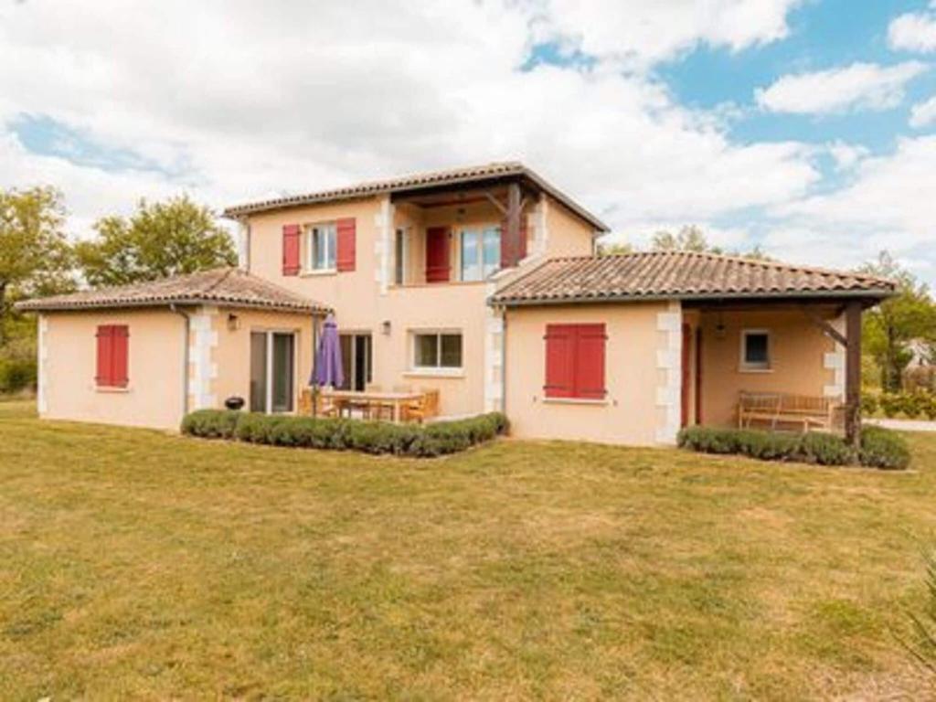 una casa con puertas rojas en un campo de césped en Spacious and modern villa with large garden and BBQ area, en Les Forges