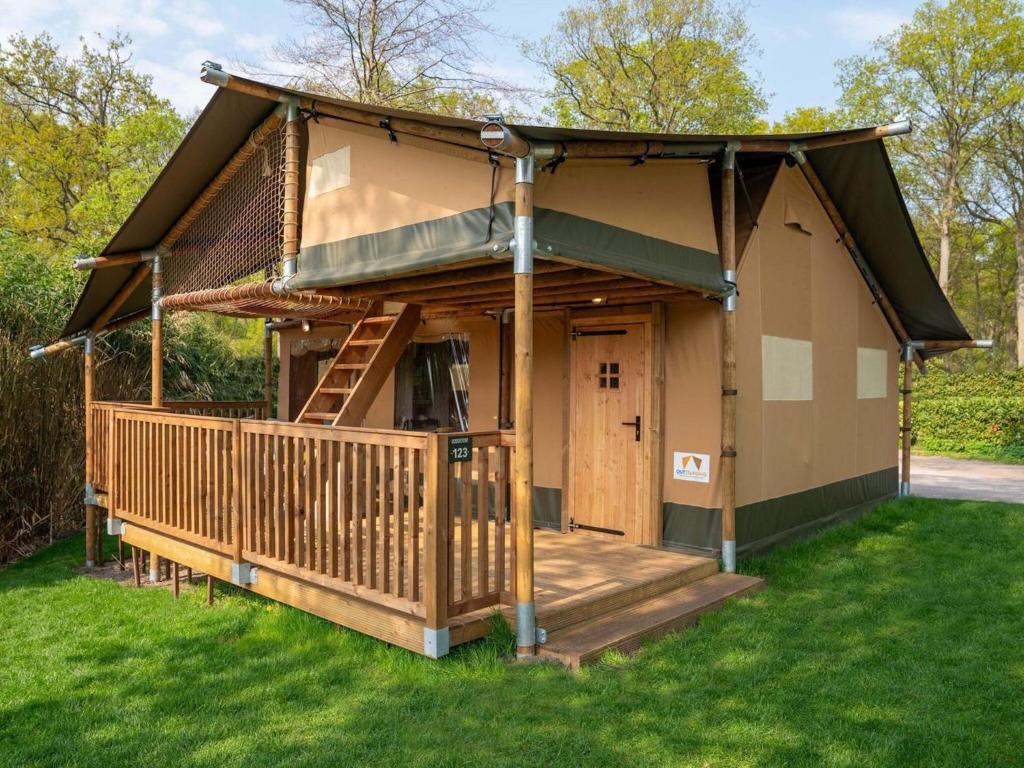 a small house with a porch and a deck at XL Glamping tent with bathroom, in a holiday park right on a recreational lake in Lathum
