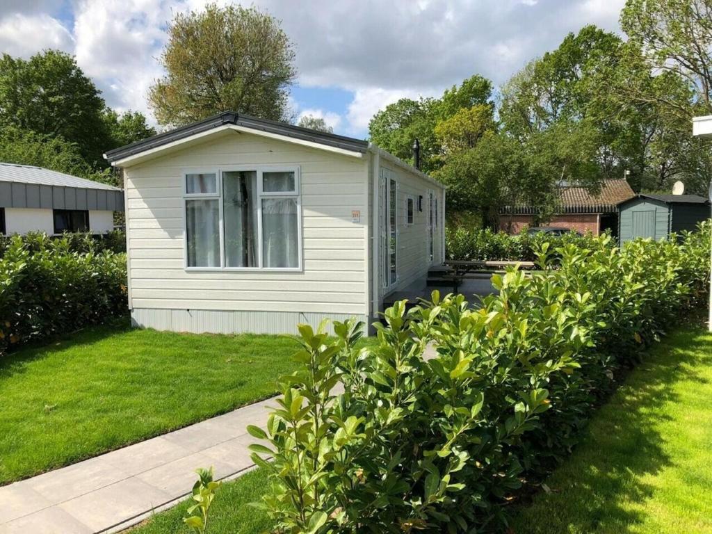 LathumにあるComfort chalet with dishwasher on a holiday park directly at recreational lakeの芝生の小さな白小屋