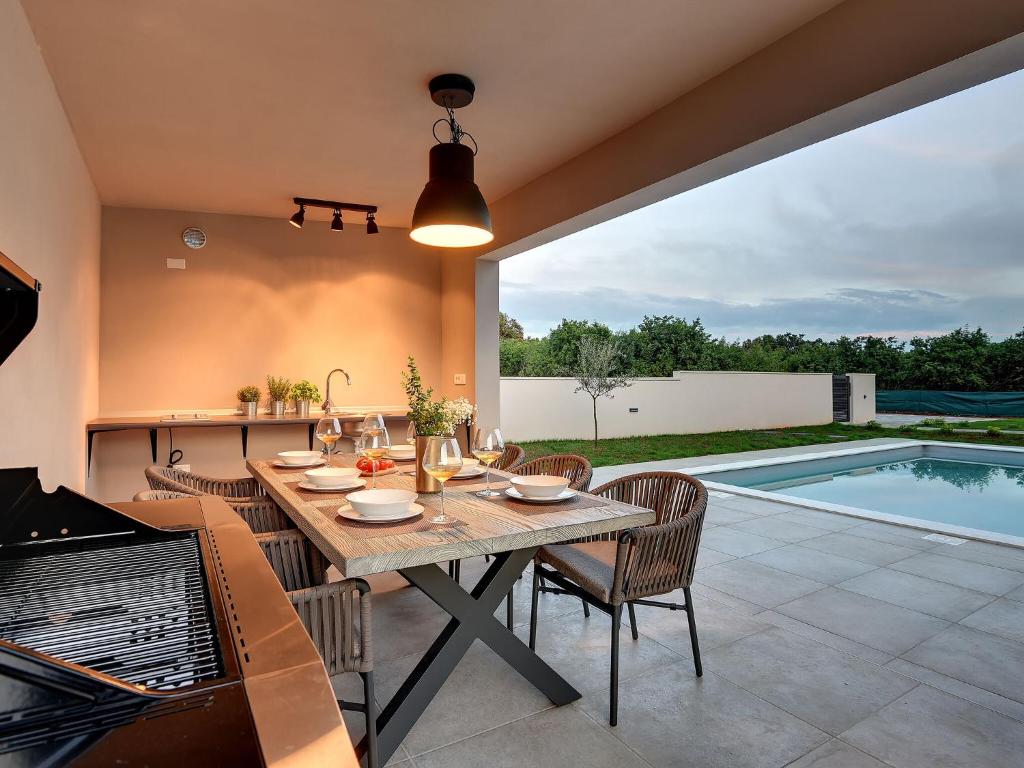 un patio con mesa y sillas y una piscina en Modern villa swimming pool , outdoor kitchen and fenced garden en Pula