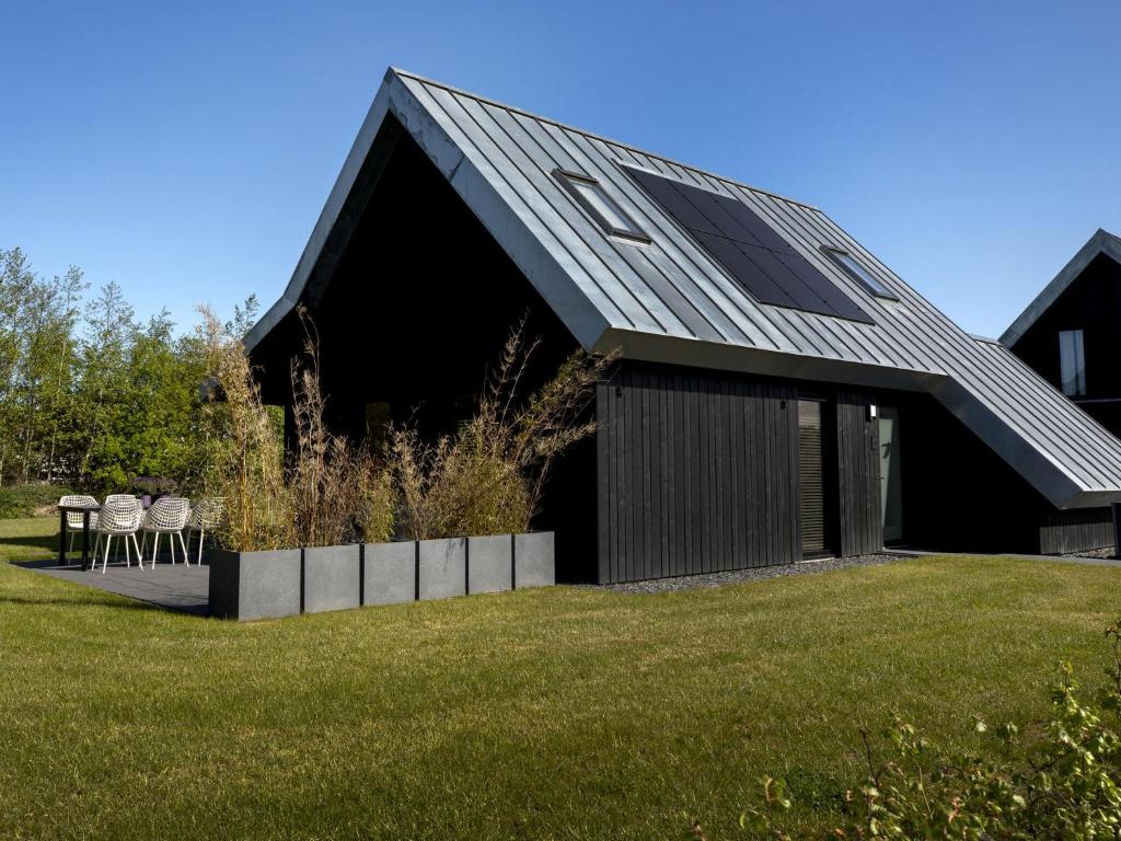 a black house with a roof on a grass field at Modern villa with spacious garden, on a holiday park in Friesland in Sint Nicolaasga