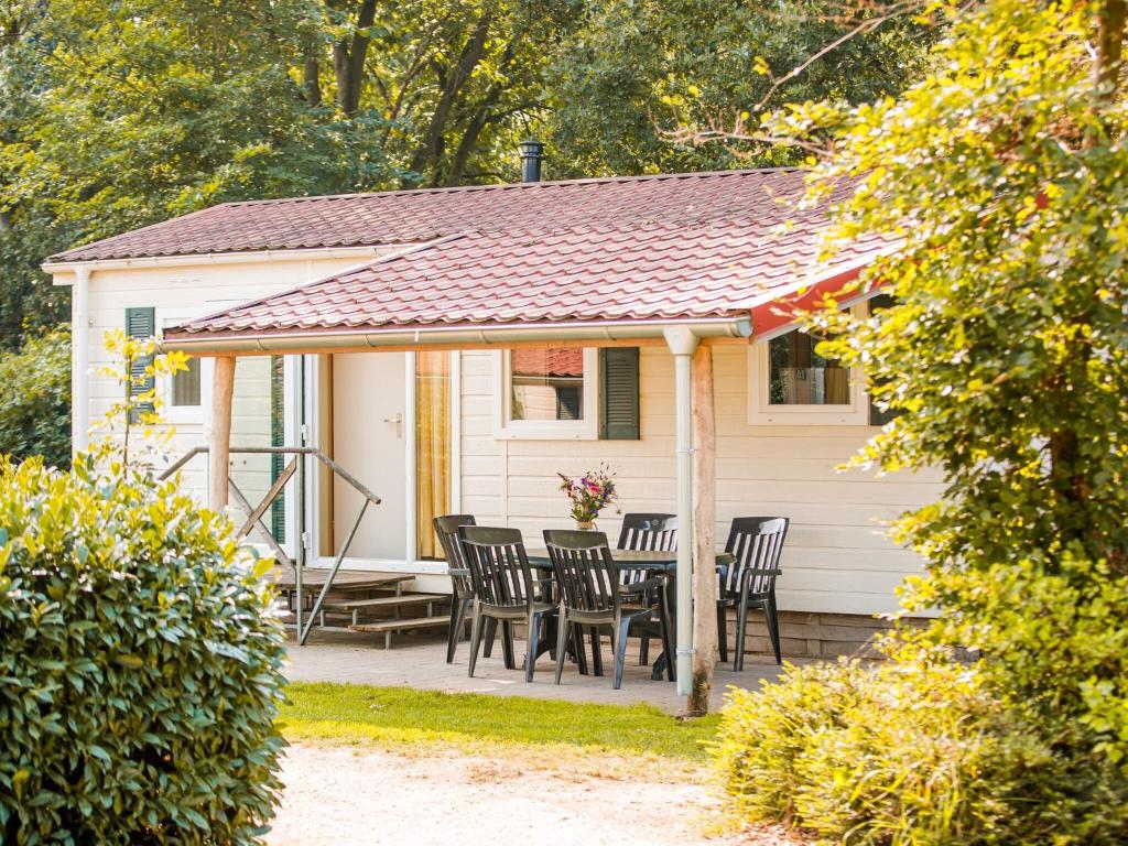 une maison blanche avec des chaises et une table dans l'établissement Cozy chalet with covered terrace in a holiday park on the Leukermeer, à Well