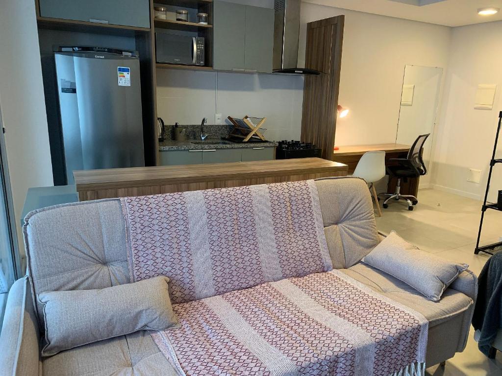 een woonkamer met een bank met een deken erop bij Encantador,Novo,Central,Com Garagem e Wifi 300Mbps in Pelotas