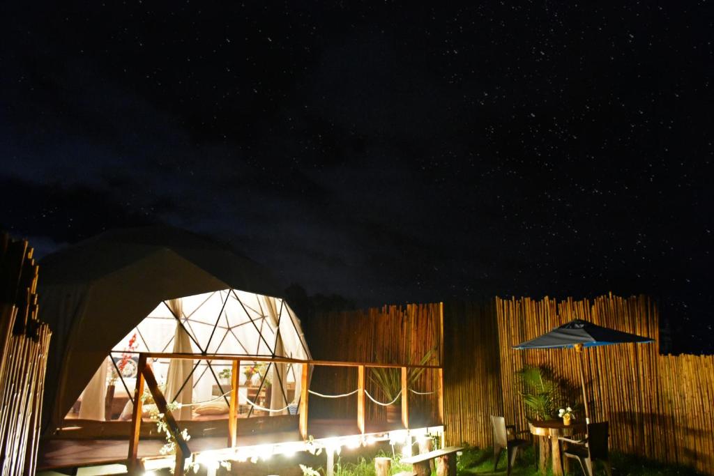 a yurt with a table and an umbrella at night at Glamping Claro de Luna in Guatavita