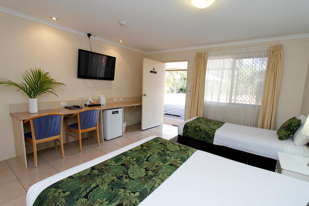 Habitación de hotel con 2 camas y escritorio en The Palms Motel, en Chinchilla
