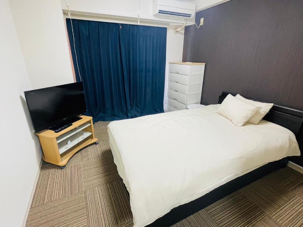 a bedroom with a bed and a flat screen tv at SUNPIA WOMBLE GATE l 大滝町 in Kusugaurachō