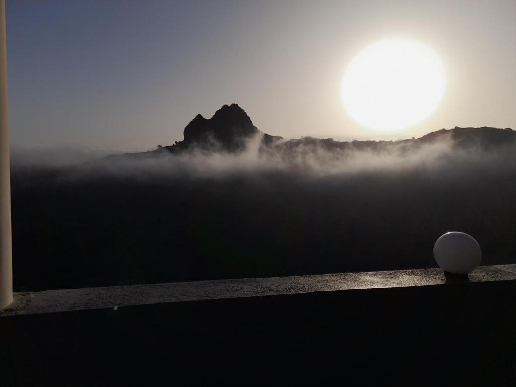a misty view of a mountain with the sun in the background at Splanada poilon in Assomada