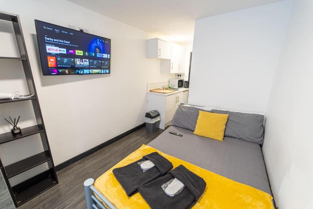 um pequeno quarto com uma cama e uma televisão em Ground floor studio close to the city! em Birmingham