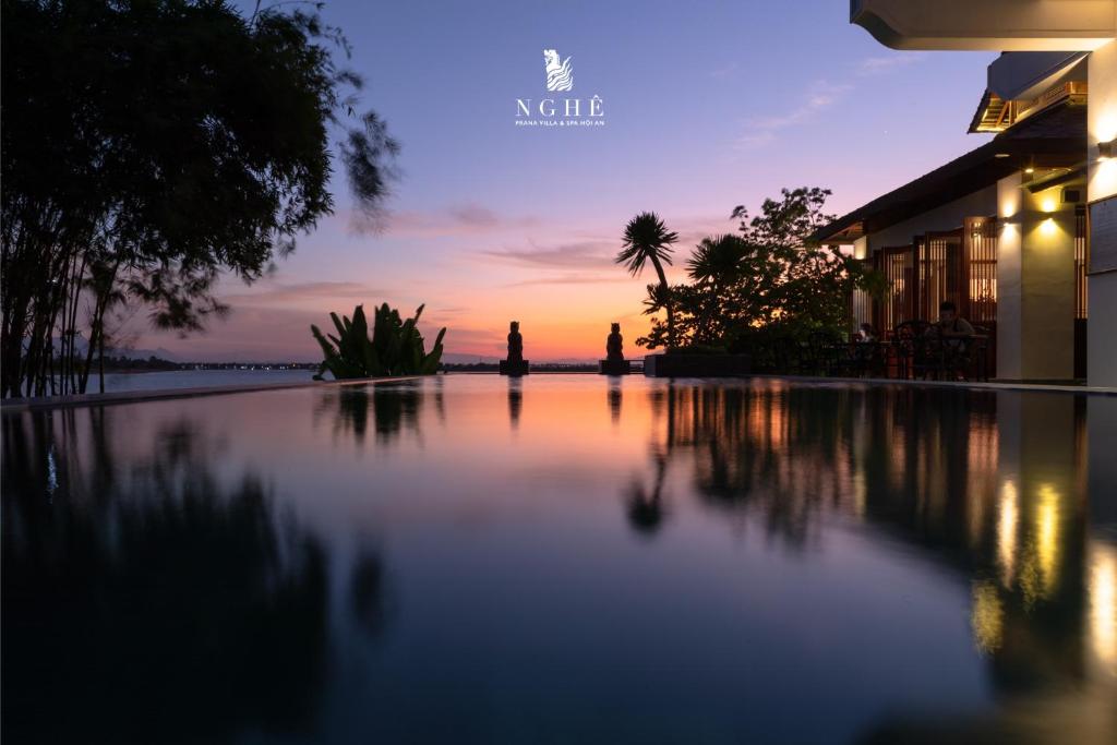 einen Sonnenuntergang über einem Pool in einem Resort in der Unterkunft Nghê Prana Villa & Spa Hoi An in Hoi An