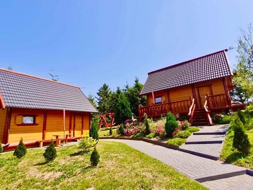 une cabane en rondins avec un jardin et une maison dans l'établissement R&S Domki, à Darłowo